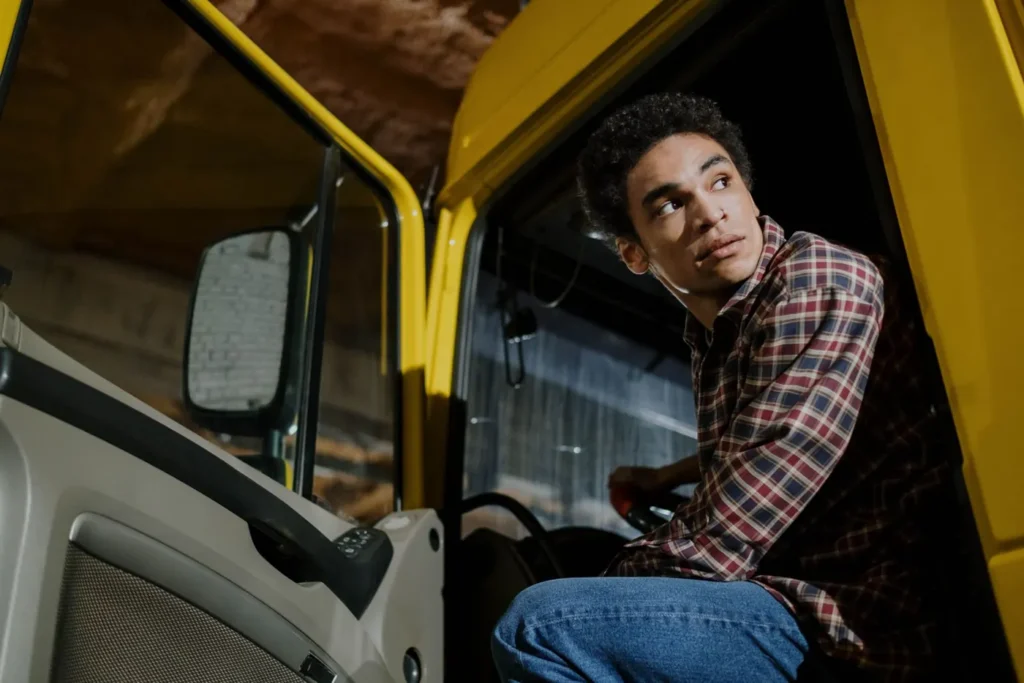 Jeune chauffeur assis dans la cabine d’un camion jaune