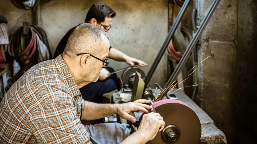 Deux ouvriers à la meule dans un atelier