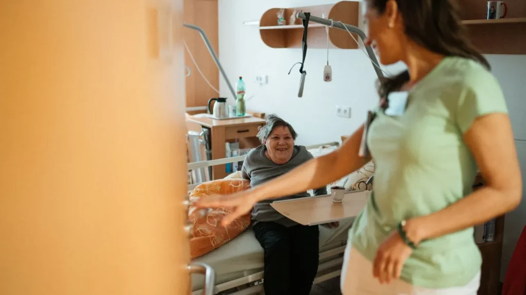 Soignante qui entre dans la chambre d’une résidente souriante